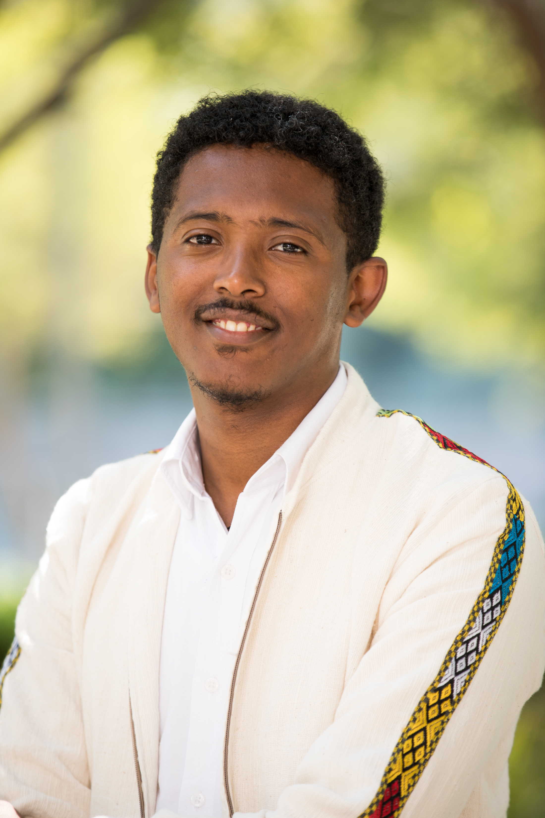 Beniam Darge is smiling n a cream jacket and white button down shirt.