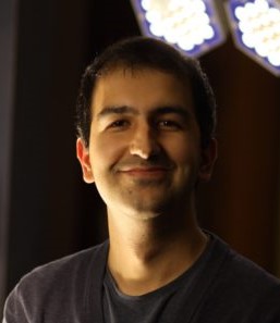 Photo of Bekir Altas, PhD wearing a gray tee shirt front of a dark background 