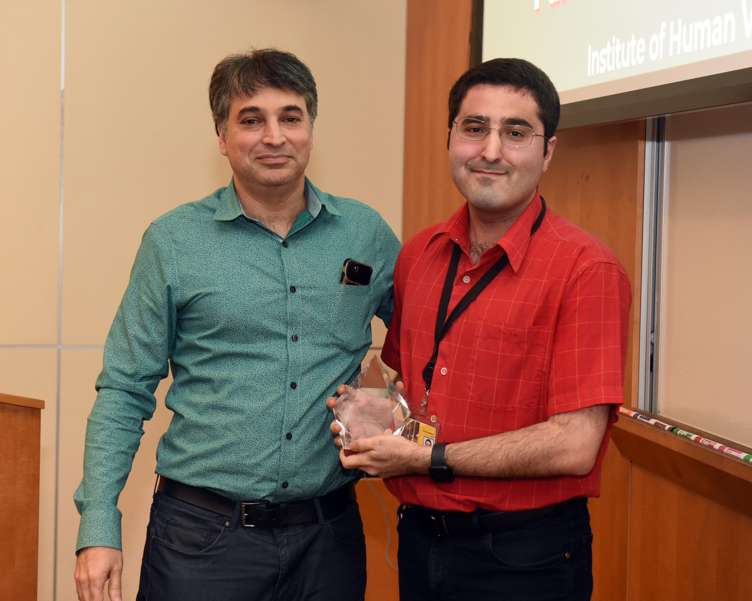 Dr. Parham Habibzadeh and Dr. Mohammad Sajadi stand next to each other. Dr. Sajadi is holding Dr. Parham Habibzadeh's Postdoctoral Service award
