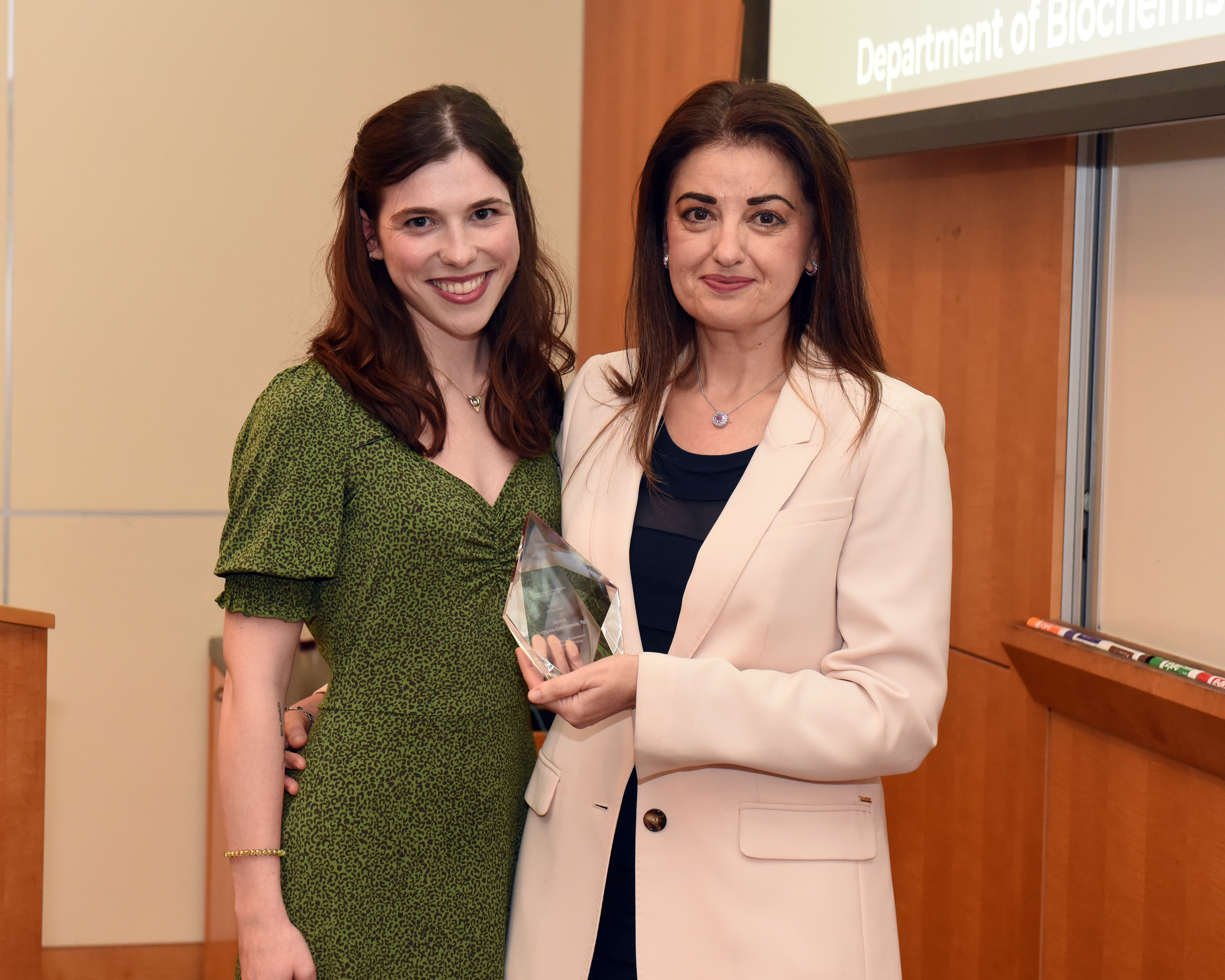 Annie Brong and Dr. Aikaterini Kontrogianni-Konstantopoulos stand together. Dr. Aikaterini Kontrogianni-Konstantopoulos is holding her Teacher of the Year Award.