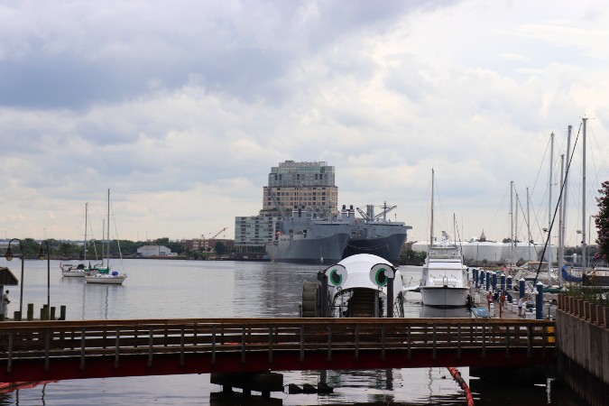 Mrs Trashwheel,a bridge, military ships, sailboats in the Inner Harbor, and Silo Point apartment building in background